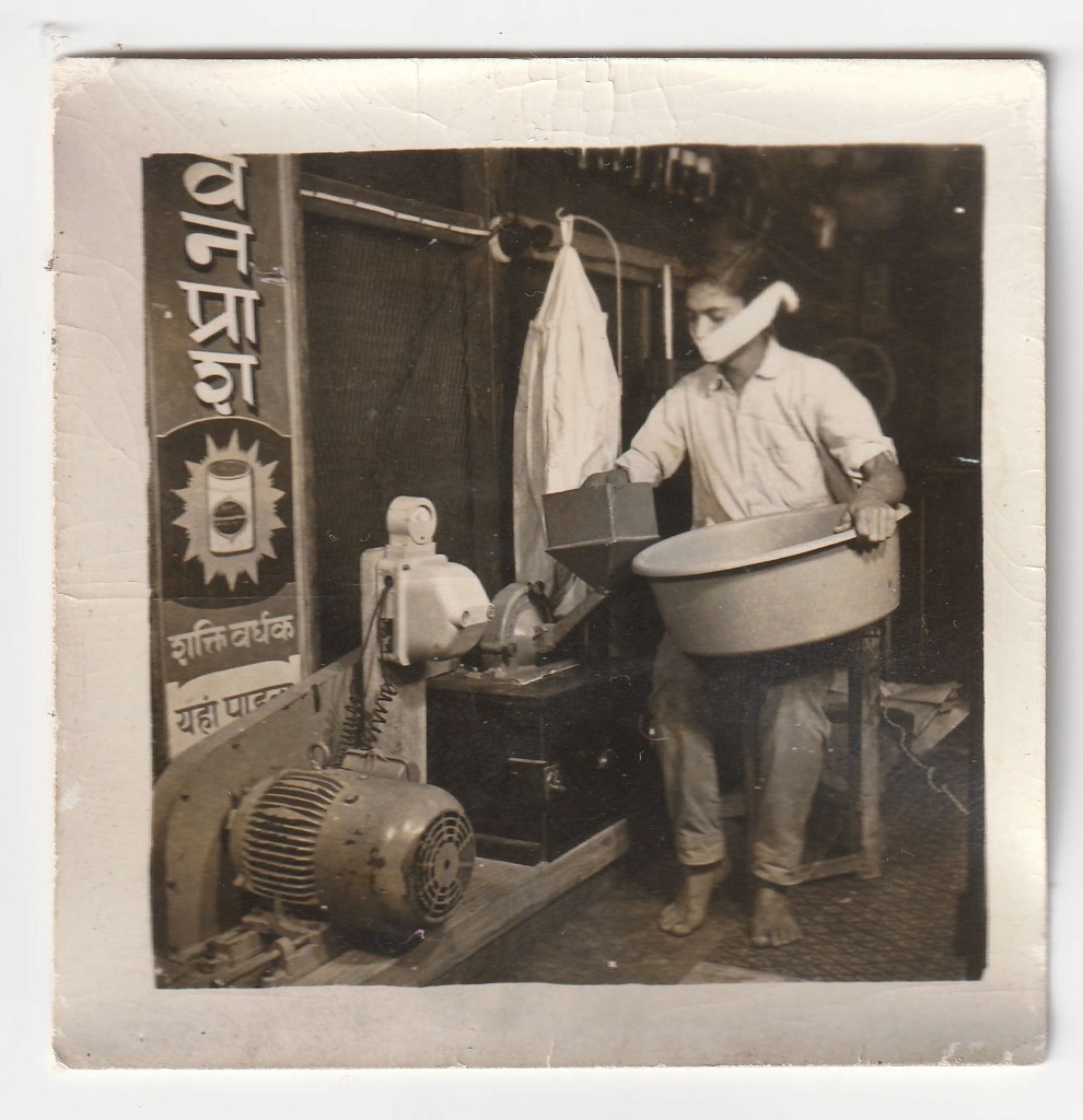 Operating an electric grinding mill inside the compounding room. Date unrecorded.