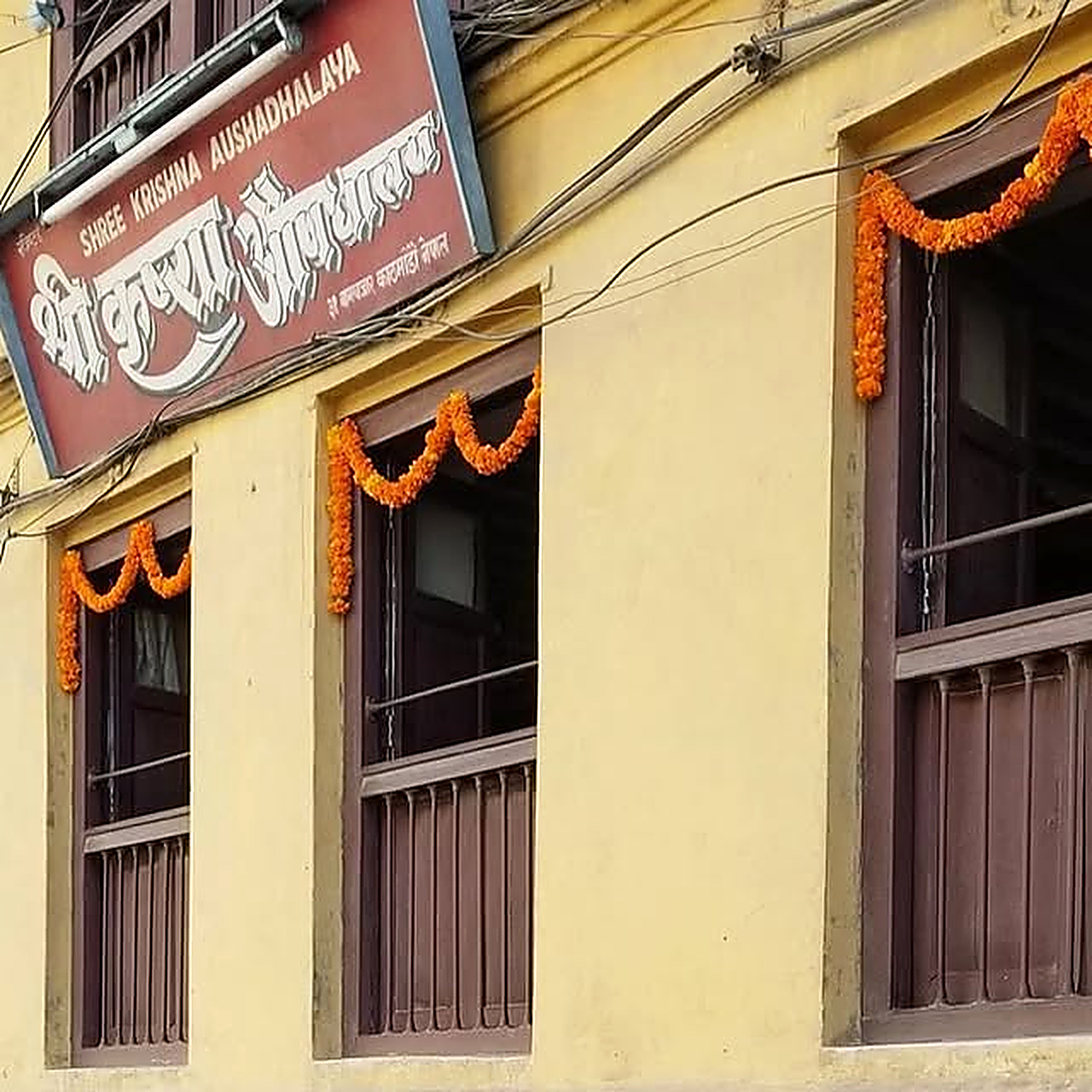 Upper facade of dispensary adorned with festive marigold garlands in Bagbazar
