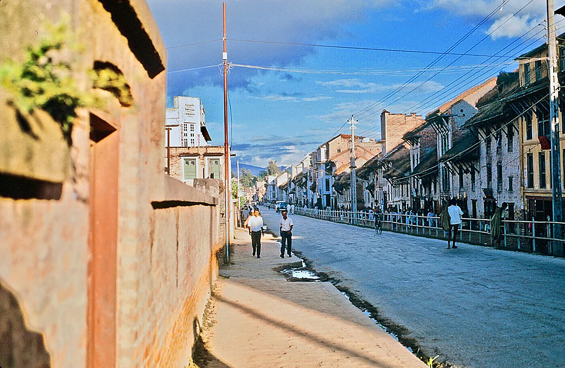 Archival color photograph of Bagbazar road in 1968 AD (2025 BS), showing pedestrians and Shree Krishna Aushadhalaya shop in the right foreground corner