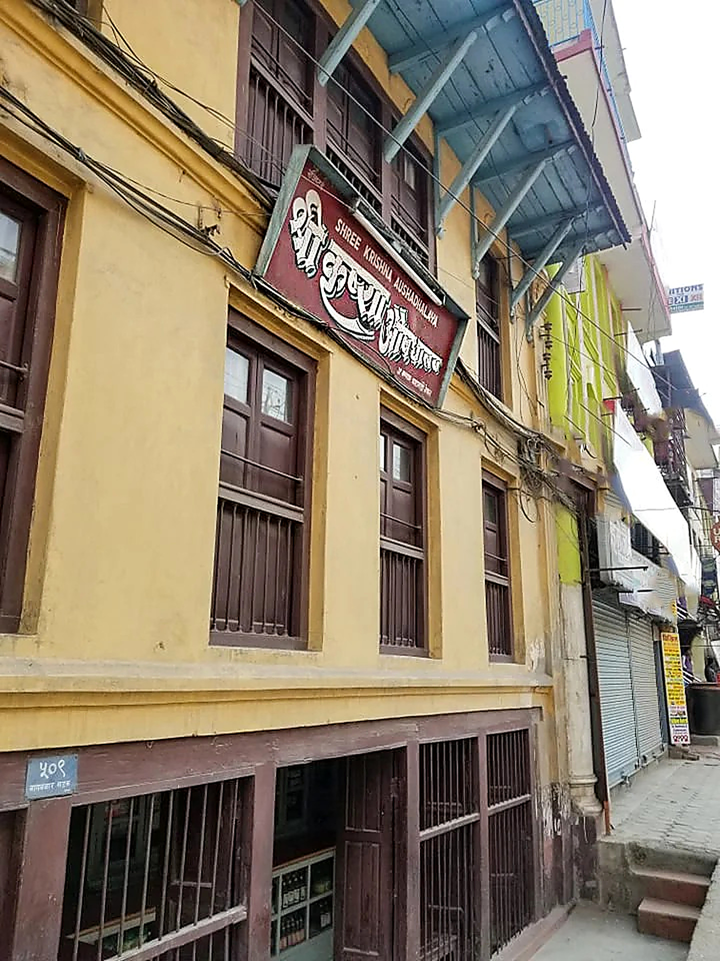 Street-level view looking up at entrance door #509 of Shree Krishna Aushadhalaya
